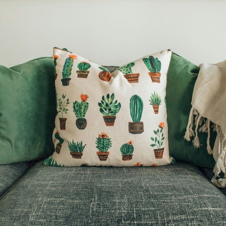 Coussin imprimé de cactus posé sur un canapé gris