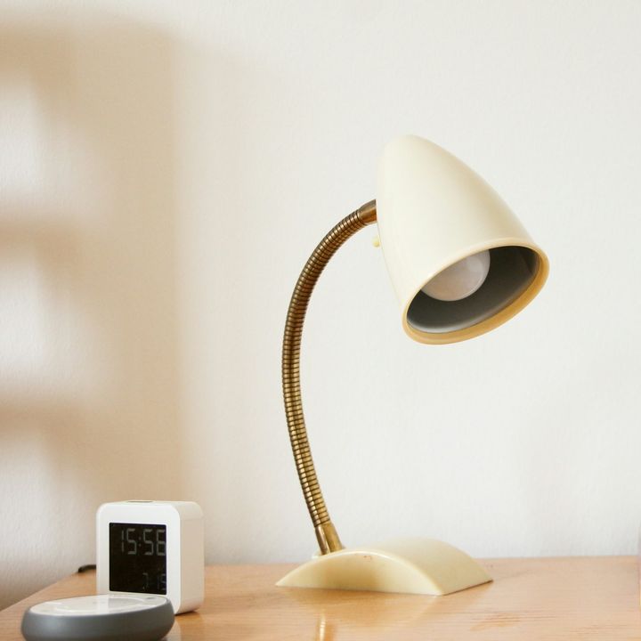 Lampe de bureau crème à bras flexible, posée sur une table en bois