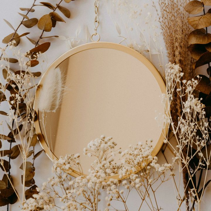 Miroir rond à cadre doré entouré de fleurs séchées